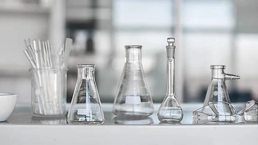 Conical flasks, volumetric flasks and pipettes arranged on a clean laboratory bench